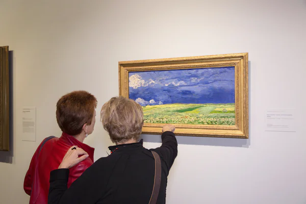 Twee vrouwen kijken naar het schilderij 'Korenveld onder onweerslucht' van Vincent van Gogh. Foto: Maaike Koning
