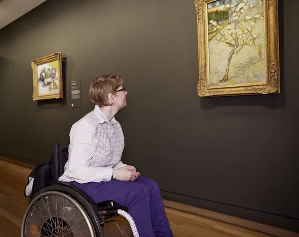 Een museumbezoeker in een rolstoel kijkt naar het schilderij Perenboompje in bloei. Foto: Maaike Koning